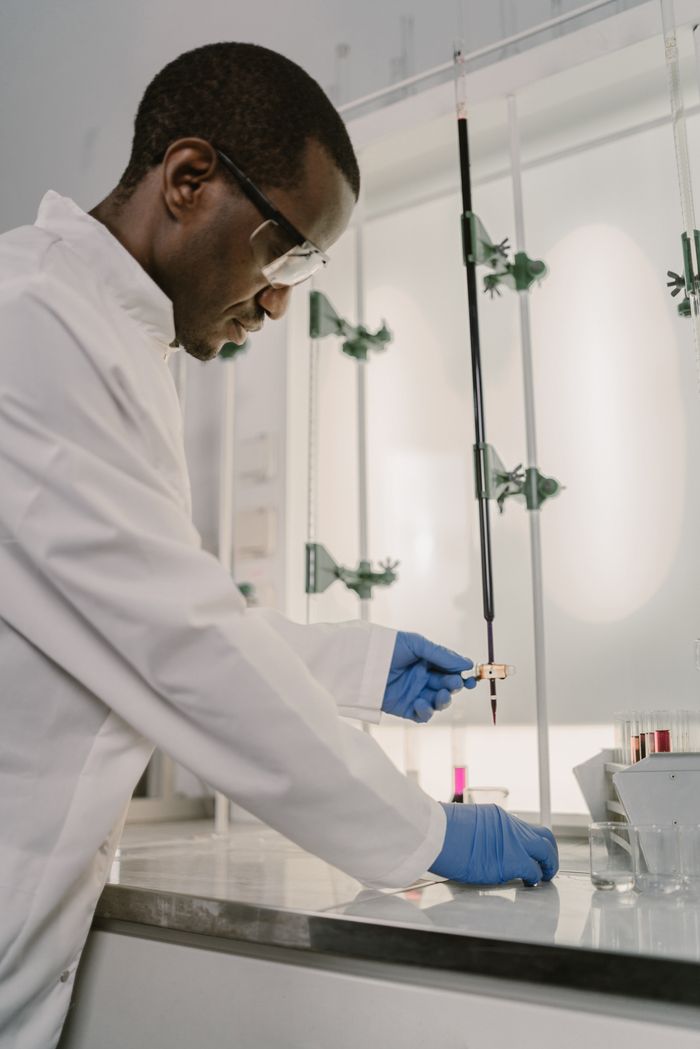A focused chemist working in a laboratory with safety equipment.